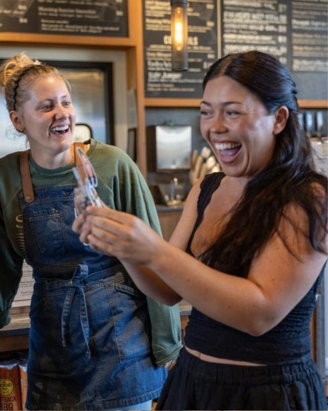 Two guests laughing over a freshly made TinyTwin bobblehead